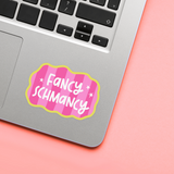 Laptop with a 'Fancy Schmancy' sticker on a pink surface