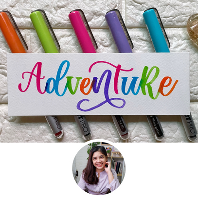Colorful markers with a sign reading 'Adventure' on a textured surface.