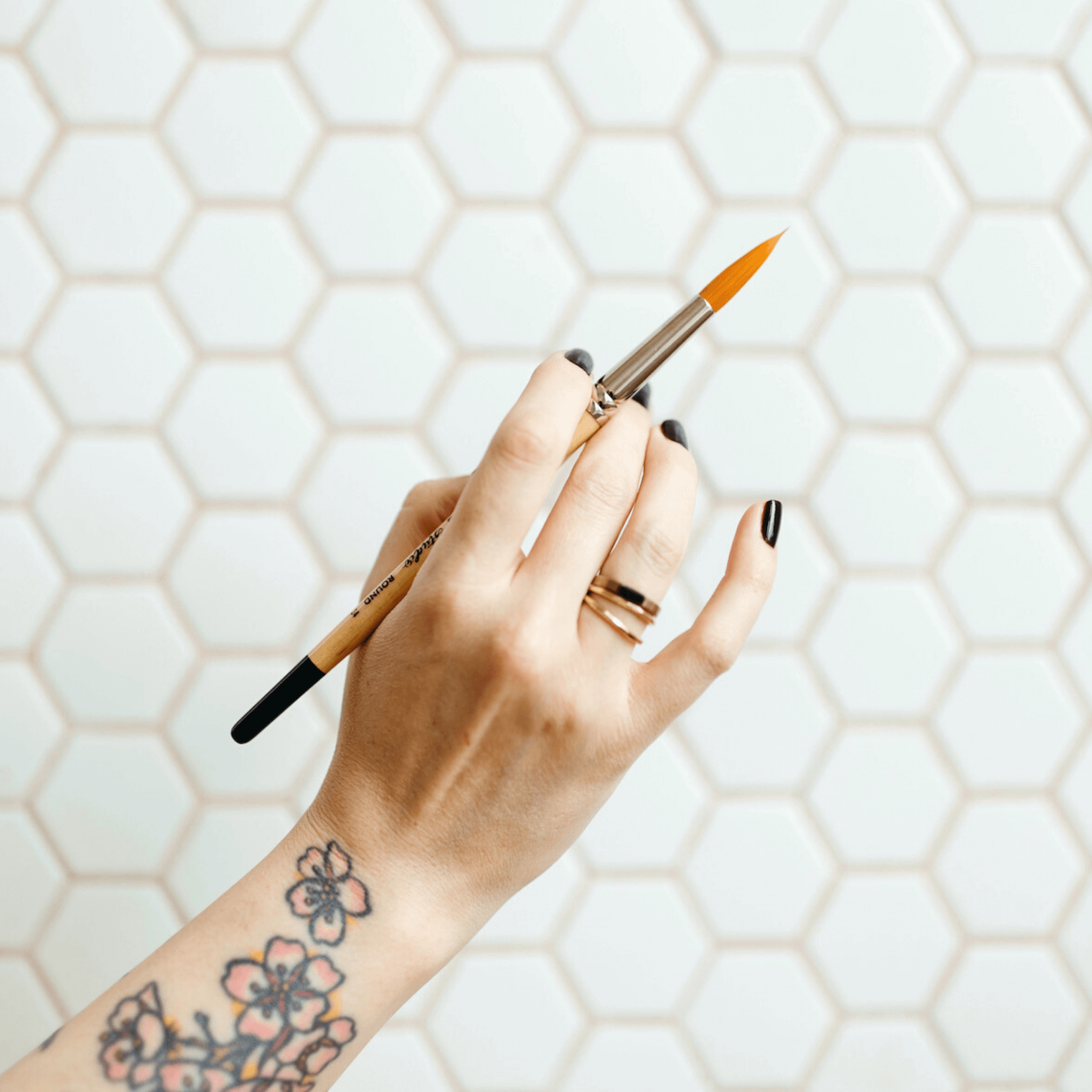 A hand elegantly holding a paintbrush